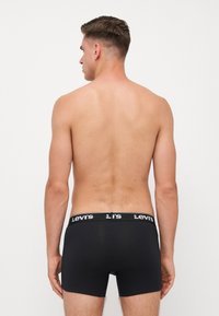 Fekete boxer alsónadrág, rugalmas anyagból készült, fehér Levi's logóval a fekete derékgumiban. Sima tapintású, testhezálló kialakítás, rövid szárakkal.