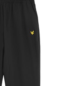 Zwarte casual broek met een elastische tailleband en een klein geel geborduurd vogellogo aan de rechterzijde bij de zak.