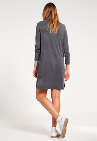 Abito a coste grigio a maniche lunghe, di lunghezza fino a metà coscia, con spacchi laterali e una vestibilità comoda, abbinato a scarpe da ginnastica bianche.