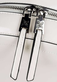 Bolso de mano de cuero sintético blanco con cremallera de dos tiradores metálicos, cada uno con acentos en blanco y negro y diseños florales grabados.
