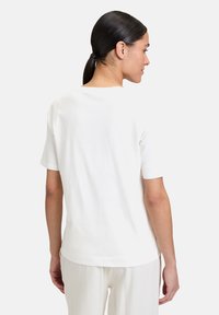 Weißes Baumwoll-T-Shirt mit kurzen Ärmeln, rundem Halsausschnitt und lockerer Passform. Die Rückseite ist schlicht mit einer glatten Textur und ohne sichtbare Muster.