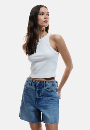Débardeur blanc à côtes associé à un short en denim bleu clair taille haute avec un ourlet effiloché. Coupe confortable avec un minimum de détails.
