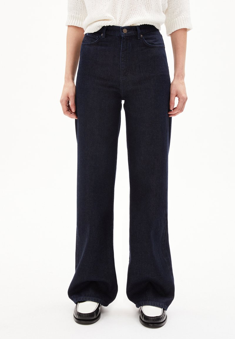 Jeans a gamba larga blu scuro con vita alta, design a cinque tasche classico e texture di denim morbido. Abbinati a scarpe nere.