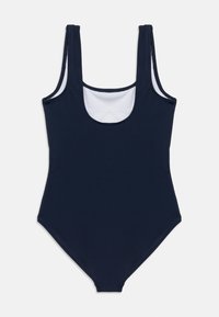 Μπλε ναυτικό ολόσωμο μαγιό με στρογγυλή λαιμόκοψη, φαρδιές τιράντες και λεία υφή. Λευκή επένδυση ορατή στη λαιμόκοψη.