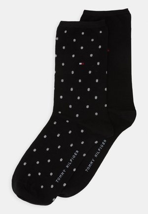 Black cotton socks featuring a polka dot pattern in gray and white. Includes branding at the cuff in white text. Soft texture.