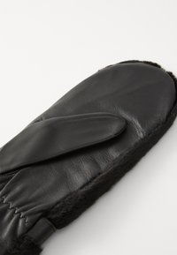 Mitten en cuir noir avec une doublure en fourrure douce, présentant un design courbé et une texture lisse. La zone de la paume est légèrement surélevée pour plus de confort.