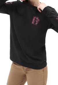 Maglia nera a maniche lunghe con logo floreale rosa sul petto e sulle maniche, scollo rotondo e tessuto morbido. Vestibilità casual con maniche a polsino.