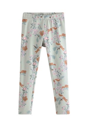 Ung pige står med benene fra hinanden iført cremefarvet langærmet skjorte med egern og blomsterprint leggings samt pink slip-on sko.