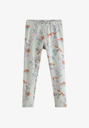 Ung pige står med benene fra hinanden iført cremefarvet langærmet skjorte med egern og blomsterprint leggings samt pink slip-on sko.