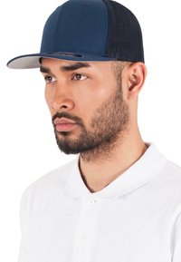 Sötétkék baseballsapka szürke karimával, hálós hátsó résszel és strukturált elülső panellel. Egy fehér pólót viselő személy hordja.