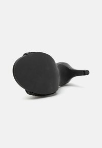 Zapato de tacón alto negro con un exterior suave, suela texturizada y un diseño elegante que presenta un tacón estrecho y un sutil detalle de costura.