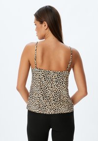 Camiseta de tirantes finos con estampado de leopardo, diseño ajustado y tela suave. La paleta de colores presenta patrones en beige, marrón y negro.