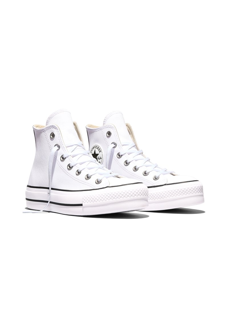Paire de baskets montantes en toile blanche avec lacets blancs, semelles en caoutchouc, détail de bande noire et logo circulaire sur le côté.