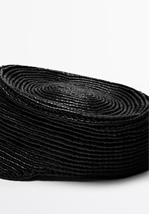 Cesto intrecciato nero, di forma ovale con superficie testurizzata. Realizzato con strisce strette, creando un design a spirale stratificato. Finitura liscia.