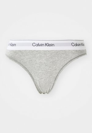Sivi pamučni tange s bijelim elastičnim pojasom na kojem je štampan logo "Calvin Klein" u crnoj boji. Glatka tekstura i uski dizajn.