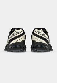 Mustvalged ja valged sportlikud jalanõud, millel on tekstuuriga võrkpealne osa, ümar kuju ning kontrastsed graafilised aktsendid kanna ja külgedel.