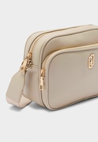 Bagno cosmetico beige con due scomparti con zip, dettagli in metallo dorato e una finitura liscia al tatto. Forma rettangolare compatta.