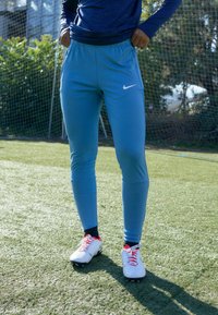 Blaue Sporthose mit schmaler Passform, aus leichtem Material gefertigt. Verfügt über eineFronttasche und ein weißes Nike-Logo am Oberschenkel.