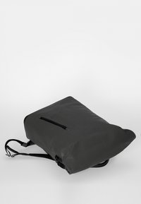 Zwarte rugzak met een gladde, matte afwerking, voorzien van een voorvak met rits en verstelbare banden. Eenvoudig, functioneel ontwerp.