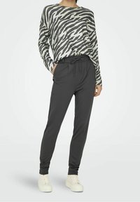 Grå och vit zebra-randig långärmad skjorta som matchas med mörkgrå joggerbyxor med dragsko i midjan och mudd vid anklarna.