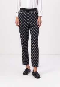 Black patterned trousers featuring a geometric design, gold hardware accents, and a fitted waist with side pockets. Smooth fabric texture.