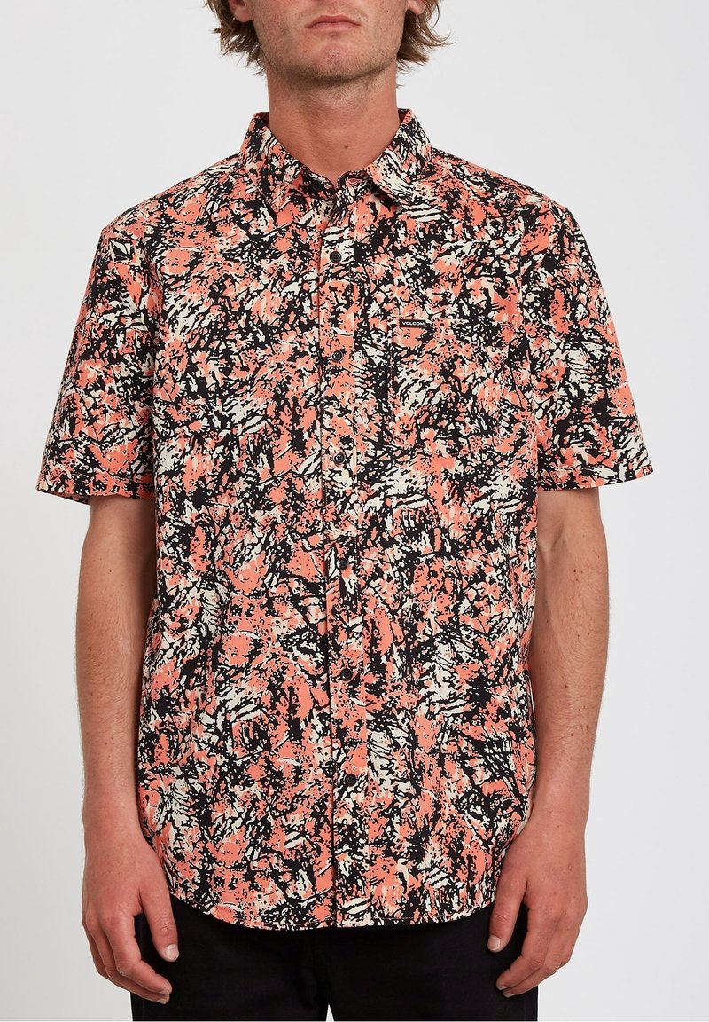 Chemise à manches courtes de couleur corail, avec un motif abstrait noir et blanc ; design à boutons, poche poitrine gauche et tissu texturé.