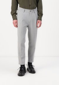 Gray, tailored trousers with an elastic waistband, featuring a front button closure and side pockets, paired with black lace-up shoes.