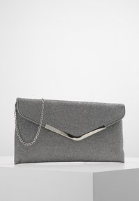 Sac pochette en tissu gris avec un rabat anglé, un accent métallique et une bandoulière chaîne. Présente une surface texturée et une silhouette élégante.