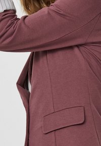 Lekka, teksturowana bordowa marynarka z pojedynczą kieszonką, dopasowany kształt i miękka tkanina, z częściowym widokiem na rękaw.