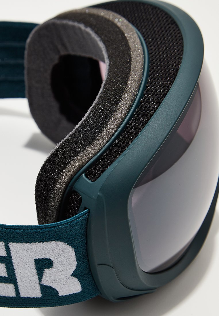 Skibril met een donkerblauw frame, grijze schuimvoering en een reflecterende lens. Voorzien van een brede, verstelbare band met witte tekst.