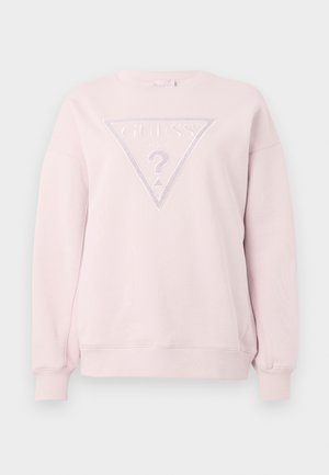 Šviesiai rožinė ilgomis rankovėmis džemperis su raukinėtais rankogaliais ir apatine dalimi, kuris turi didelį įspaustą Guess logotipą su klausimo ženklu centre.