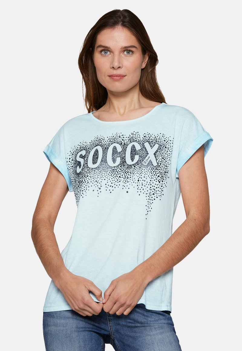 Light blue cotton t-shirt with rolled sleeves, featuring "SOCCX" in bold letters and a gradient of small black dots beneath the text.
