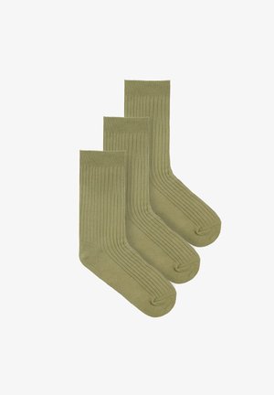 Trzy pary oliwkowozielonych, prążkowanych skarpet do kostki, ułożonych diagonalnie na białym tle.