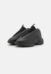 Baskets de sport noires avec un design texturé et moulé. Fabriquées en matériau synthétique, dotées d'accents en maille et d'une semelle rembourrée pour un confort optimal.