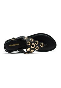 Sándalo de cuero negro con acentos circulares dorados, diseño de doble tira, suela plana y cierre de hebilla. Marca "Gioseppo" en la plantilla.