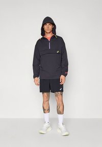 Black half-zip hooded jacket with colorful accents, paired with black shorts. Athletic fit, lightweight fabric, and logo detail on clothing.