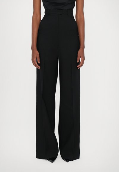 Pantalons noirs taille haute avec une silhouette à jambe large, fabriqués dans un tissu lisse, dotés d'une ceinture et de plis subtilement placés à l'avant.