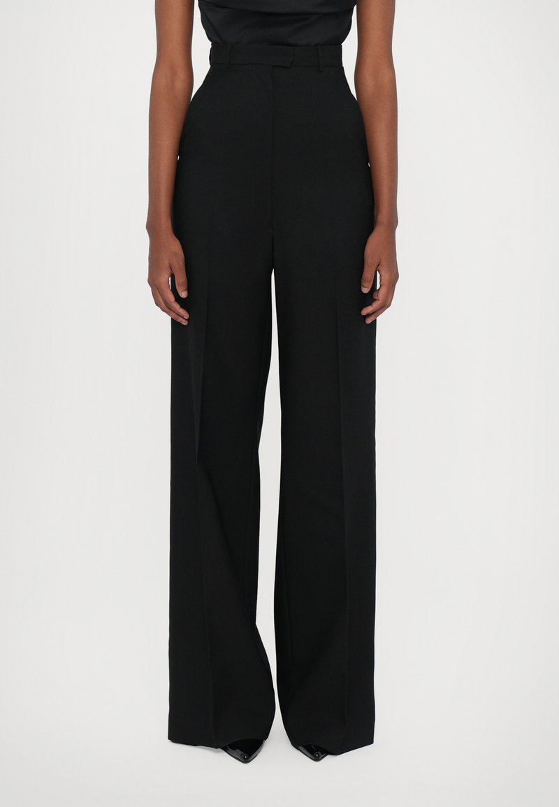 Black high-waisted trousers with a wide-leg silhouette, made from a smooth fabric, featuring a belt and subtle front pleats.