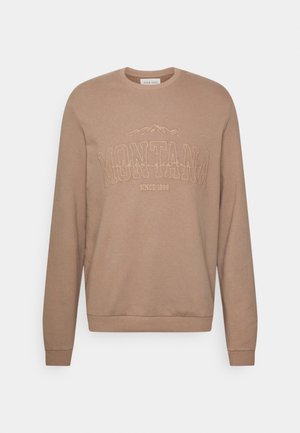 Beżowa bluza z okrągłym dekoltem i długimi rękawami, z haftowanym napisem "MONTANA", grafiką gór i napisem "Since 1986" na piersi.