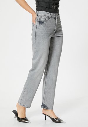 Jeans gris de tiro alto con un diseño de pierna recta, que presentan bolsillos delanteros y una textura desgastada. Llevados con zapatillas negras de puntera afilada.
