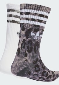 Puuvillasegu sokid, üks valge mustade triipudega, teine hall ja must leopardimustriga, millel on embleem mustrilisel küljel.