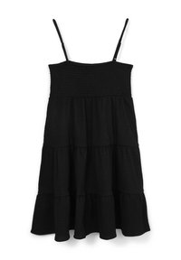 Schwarzes Sommerkleid mit dünnen Trägern, das ein gesmocabtes Oberteil und einen gestuften Rock hat. Der Stoff hat eine strukturierte Oberfläche und ein fließendes Design.