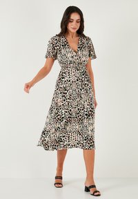 Wrap dress in lightweight fabric features a multicolored spotted pattern on a creamy background, short sleeves, and a flowy A-line silhouette.