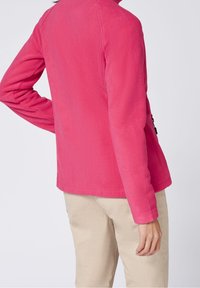 Fleece jacket in bright pink, featuring long sleeves and a rounded hem. Material appears soft with a smooth texture.