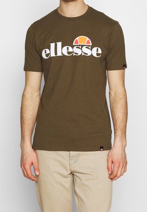 T-shirt en coton vert olive avec un grand logo "ellesse" blanc et un demi-cercle orange au-dessus. Manches courtes et coupe standard.