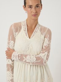 Vestido de manga larga con mangas de malla transparente, tela color crema, intrincado bordado de encaje blanco, escote en forma de V y cintura elástica.