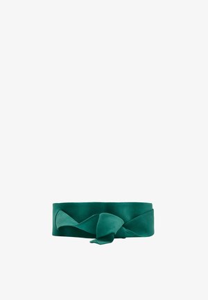 Cinturón de tela de satén verde atado en un nudo suelto con una textura ancha y suave sobre un fondo blanco.