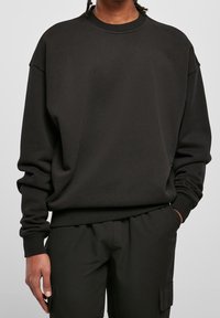 Felpa nera con scollo rotondo, vestibilità comoda e polsini a coste. Realizzata in tessuto morbido, presenta un design minimalista.