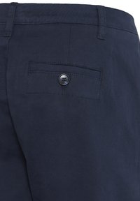 Navy-blaue Hose mit glatter Textur, ausgestattet mit einer Gesäßtasche und einem schwarzen Knopfverschluss. Einfaches Design ohne sichtbare Muster.
