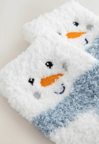 Plush white socks featuring a snowman design, with orange carrot nose, embroidered eyes, and a blue knitted patterned cuff. Soft texture.